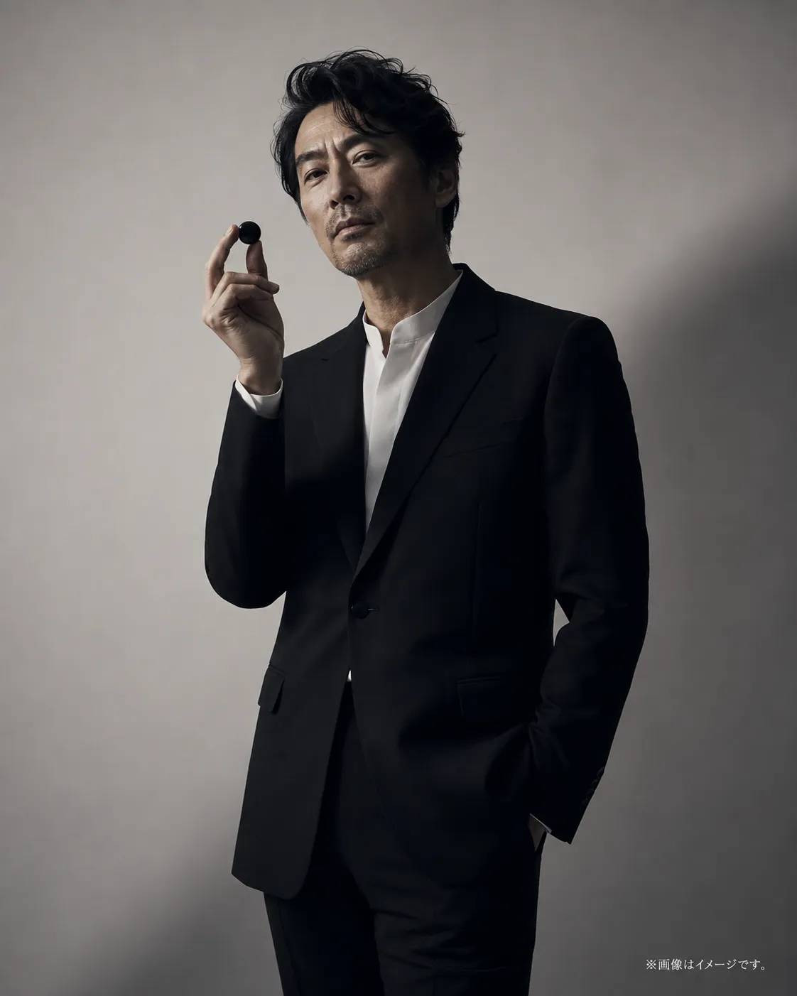 黒いスーツで碁石を持つ囲碁おじさんのイメージ